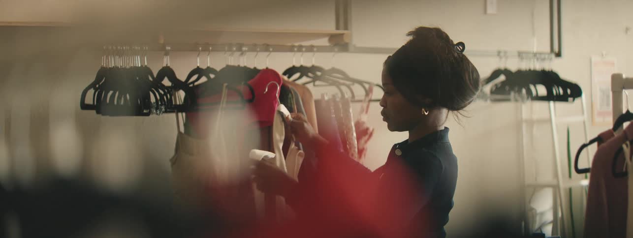A woman browses through various clothing items in a fashion store, exploring wardrobe choices and style possibilities.
