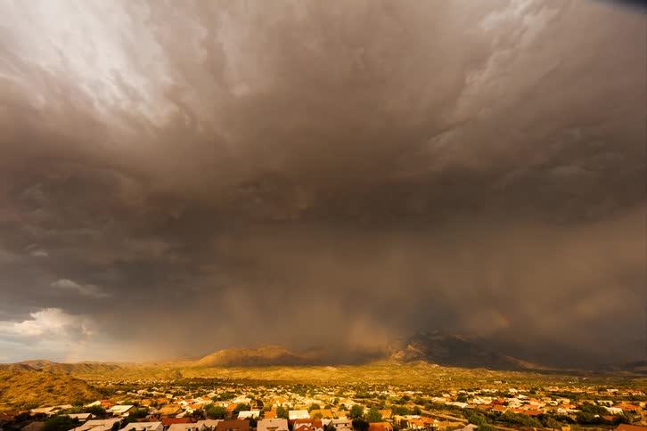 A large storm creates a rainbow over the homes