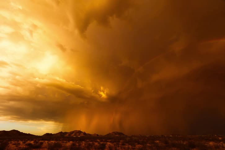 Traffic passing each other on the freeway while a storm rolls overhead