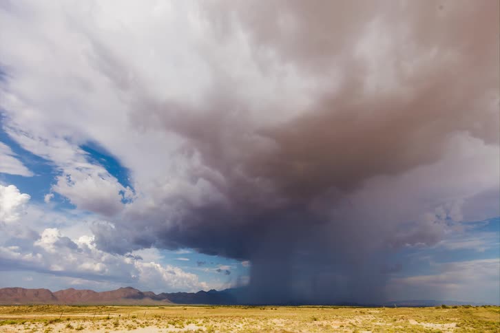 The rain clouds travel over the field