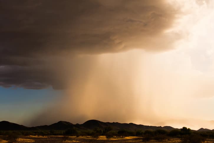 Dark storm clouds pass over the mountains on the horizon