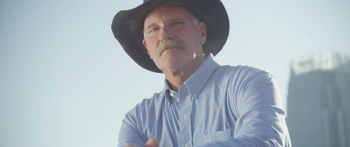 Mustached cowboy wearing a blue button-down shirt