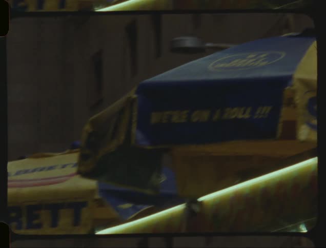 Vehicles pass a hotdog cart standing near a building downtown
