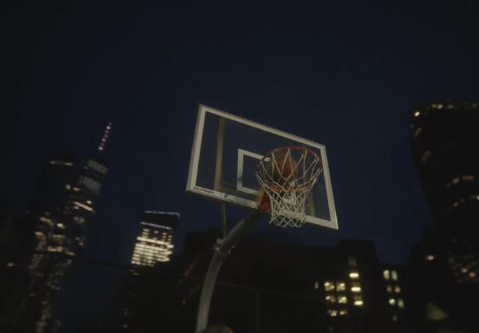 Two men are playing basketball in the city at night