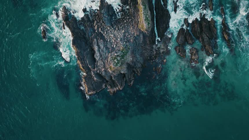 A rocky outcrop battered by waves on a turquoise ocean