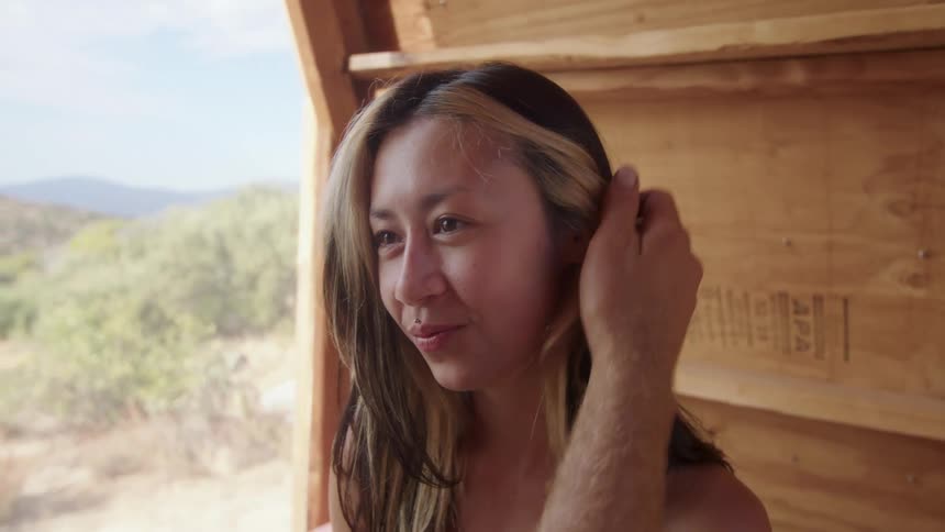 Close up of the face of a woman receives a tender caress from her partner while sitting on a wooden structure in the desert