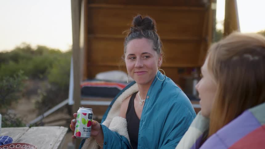 Two friends have a drink outside and talk