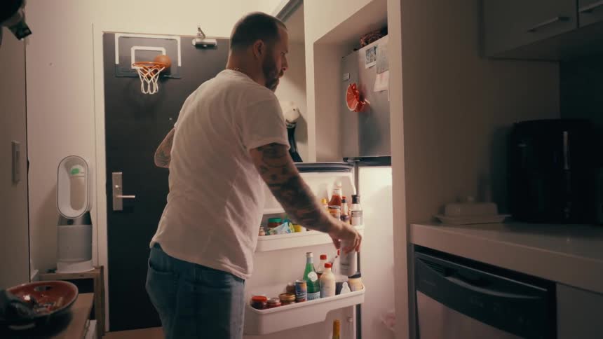 A man takes a can from a refrigerator