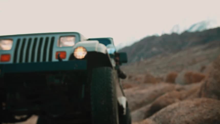 The jeep is driving over the rocks by the mountain