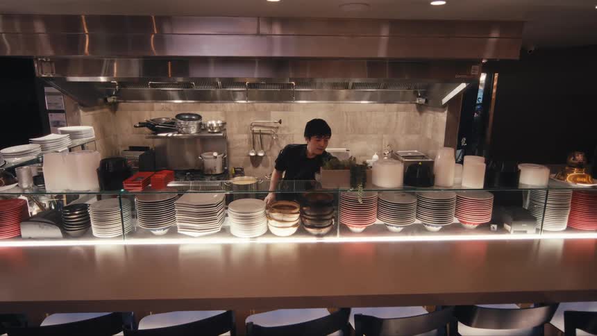 A chef grabs a plate in a restaurant kitchen