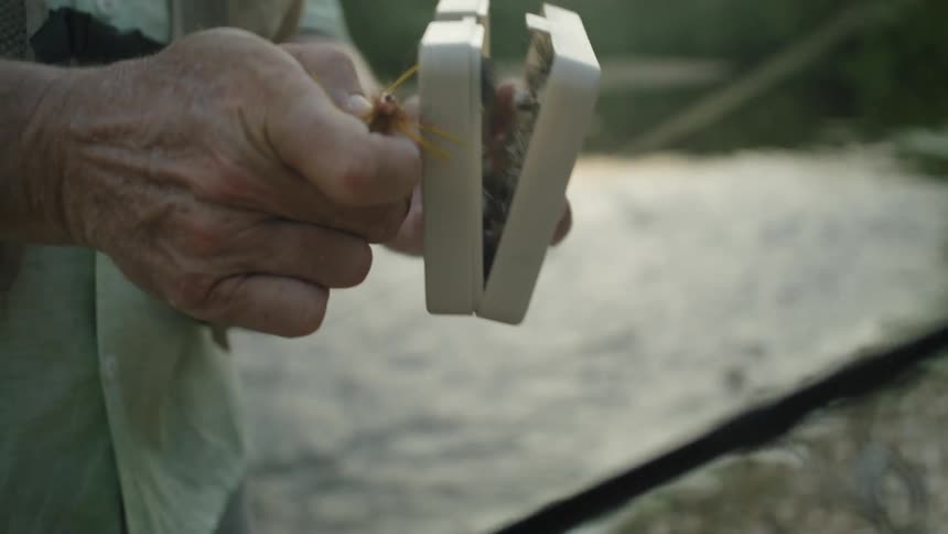 Hand picking up fishing baits inside a box