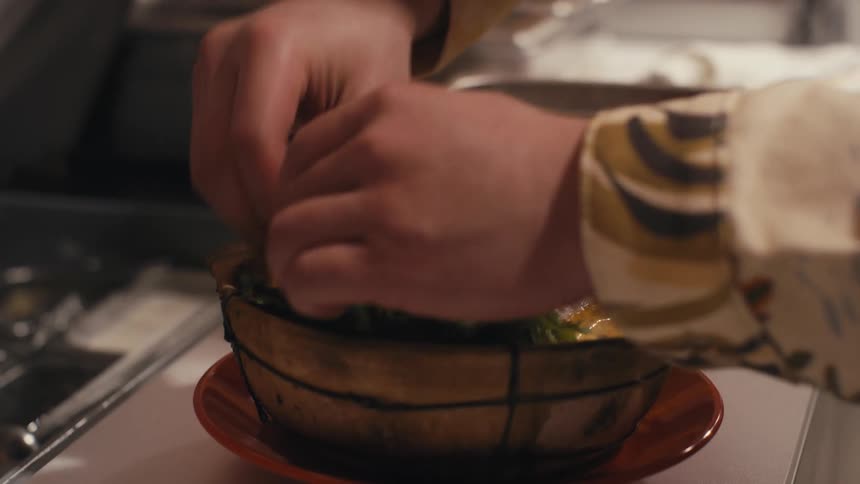 Hand preparing a dish in a restaurant kitchen