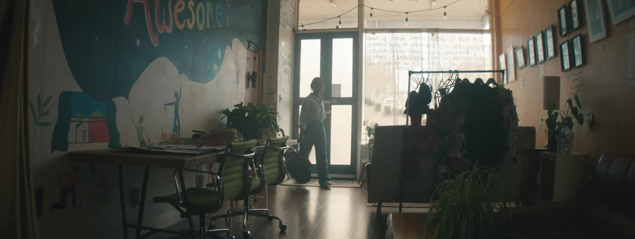 Woman entering a work environment and placing her bag on the table
