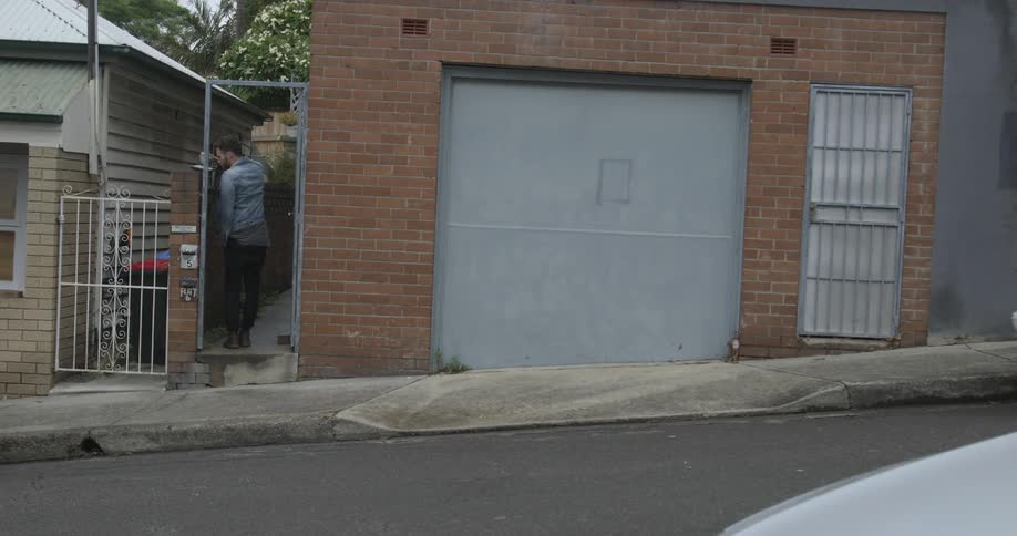 A man walking down a steeply declining street and turning into a gangway