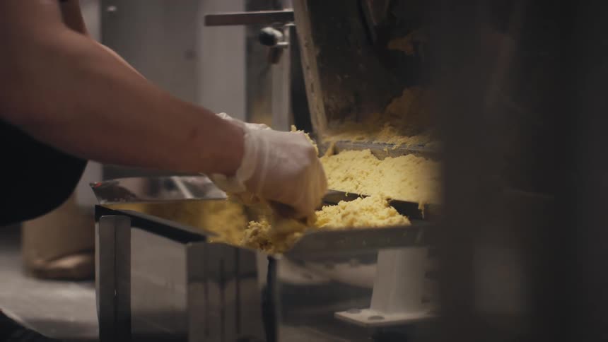 A chef is breaking apart dough at a machine in a restaurant kitchen
