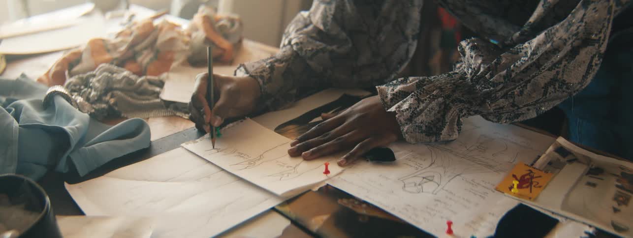 Closeup of a designers hand carefully drawing miniature dress sketches