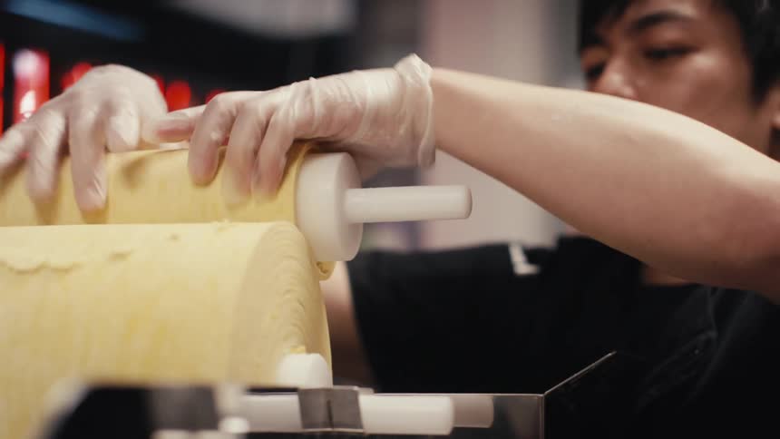 Chef with gloves rolling a handful of dough in a restaurant kitchen