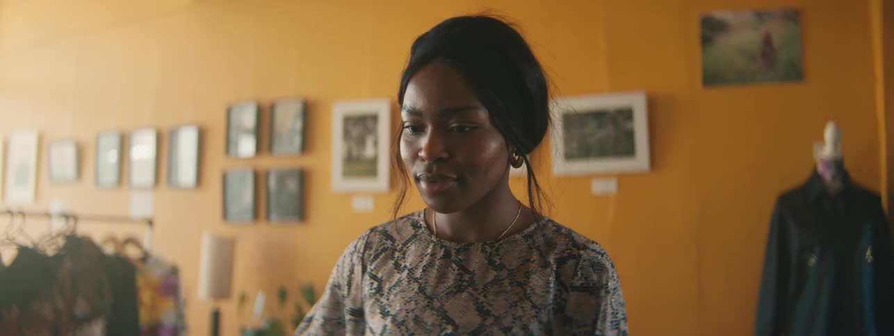 A young woman wearing a dress is looking forward and then she gives a subtle smile