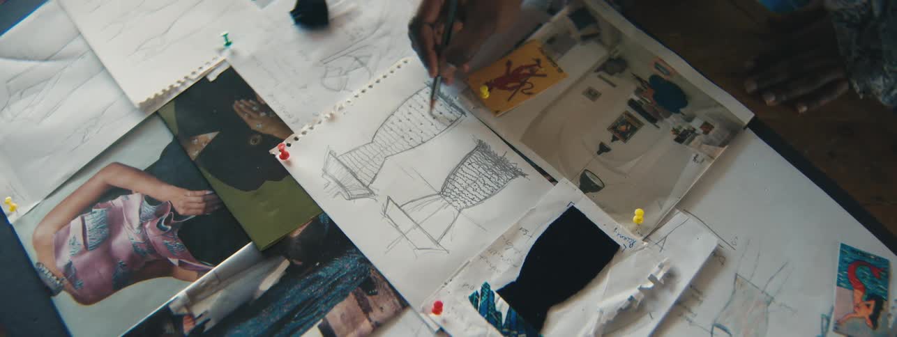 Fashion designer sketches a dress on paper at her table