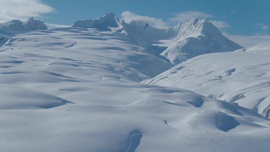 Snow covers slope leading to mountain ridge on a cloudy winter day