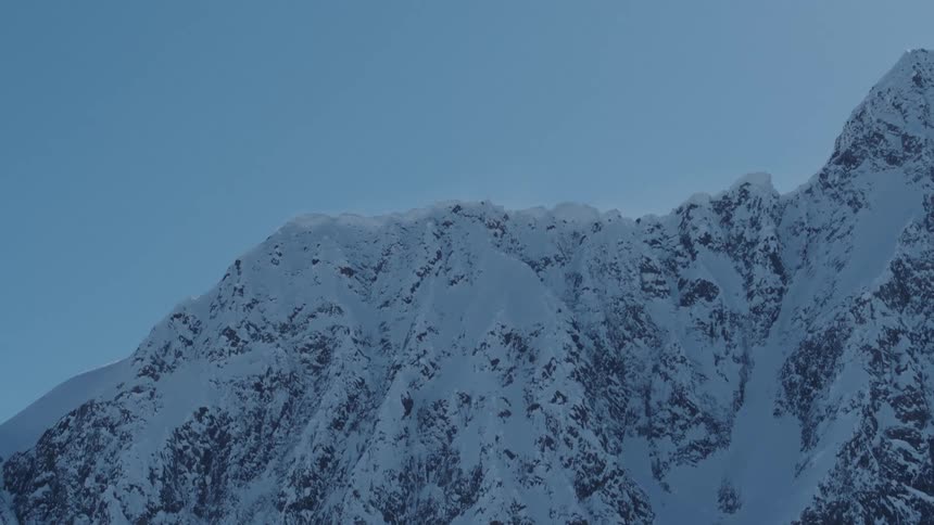 A snowcapped mountain peak against a clear blue sky
