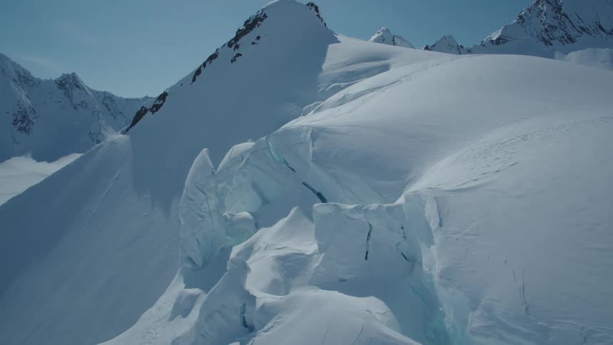 Snow crusted cliff borders steep ridge in a mountain range on a sunny winter day