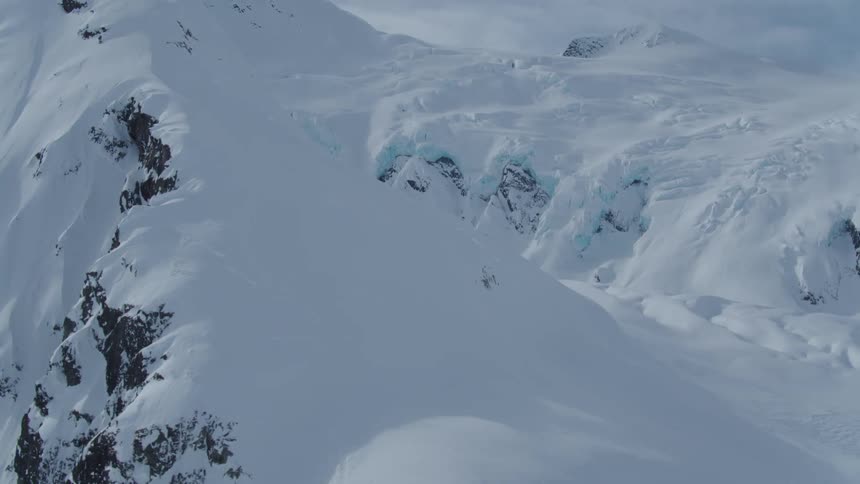 Aerial view of snow layers on mountains on a cloudy day