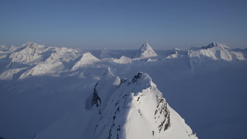 Aerial panorama of a vast field with layers of snow and mountains