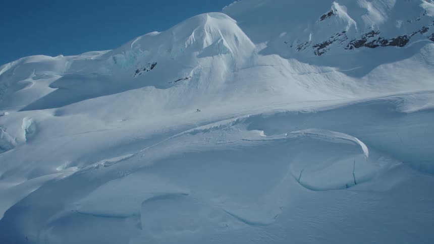 A person is driving his snowmobile through the deep snow on the mountain