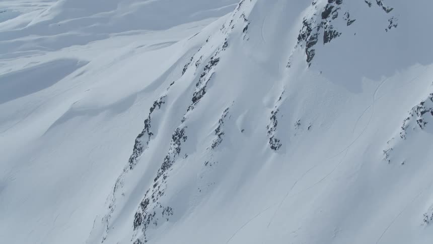 A person is skiing down a snow covered mountain from the top to the base