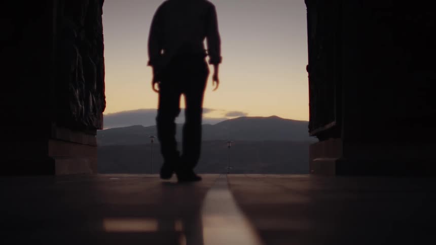 A man walks down the dark hall facing the mountain