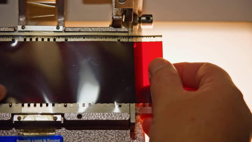 A persons hands holding a strip of film and inserting it into a film projector