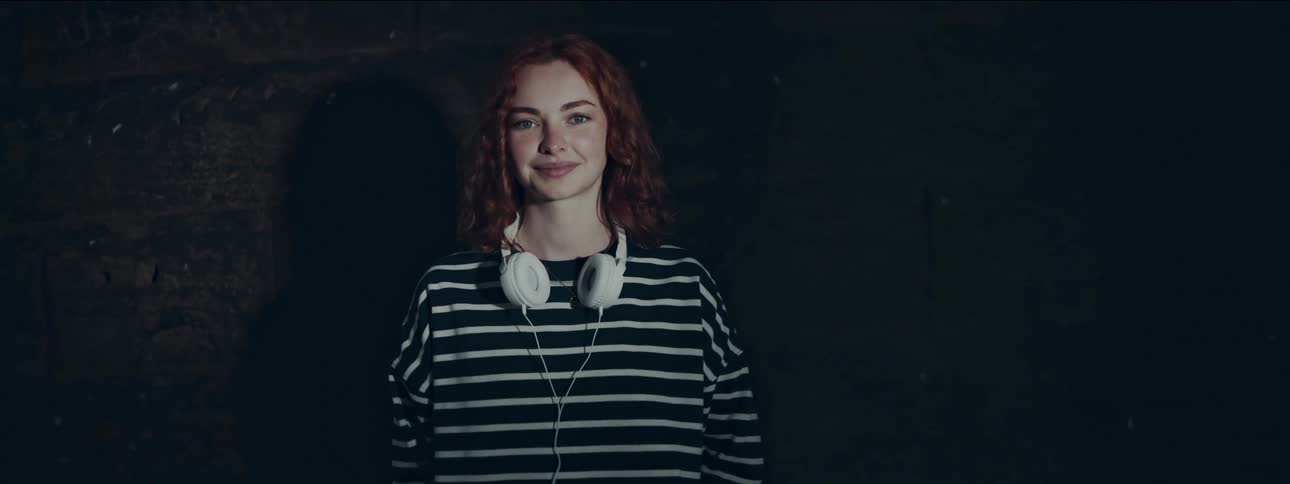 Young redhead woman with headphones giving a smile