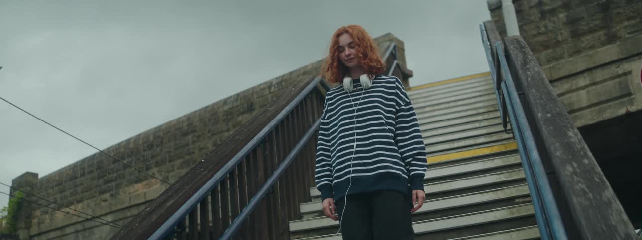 Young redheaded woman walking down the stairs of a public place