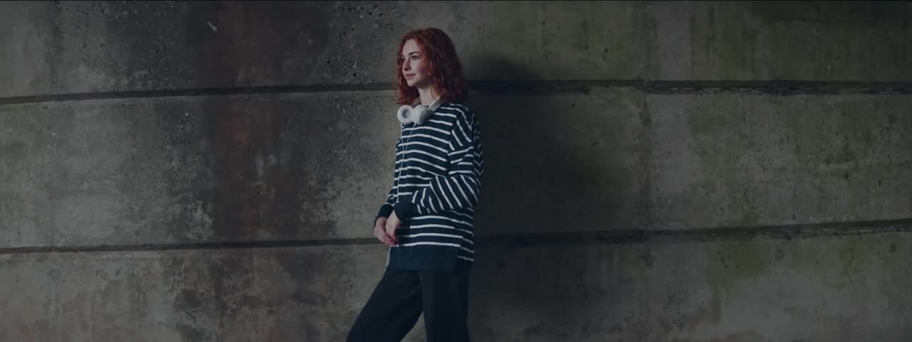 Redhead woman in a striped long sleeve blouse and white headphones