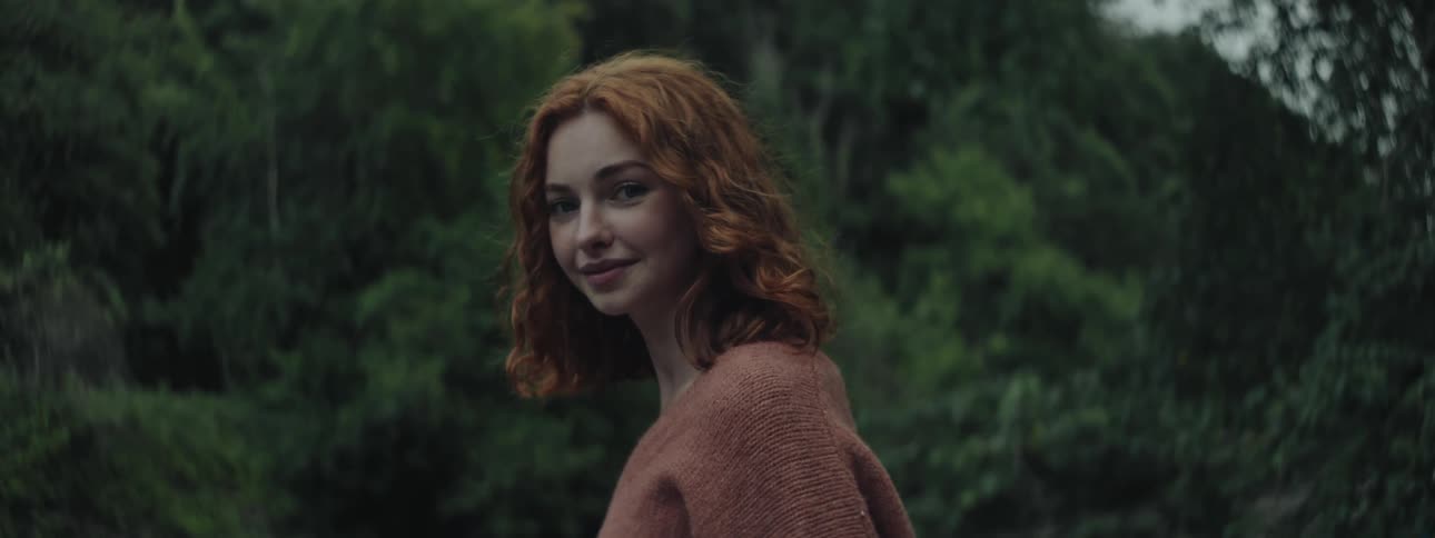 A redheaded young woman smiling then turning her head
