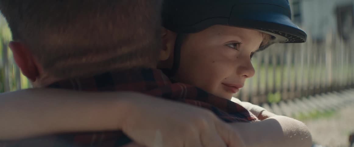 Boy wearing a helmet hugging his father