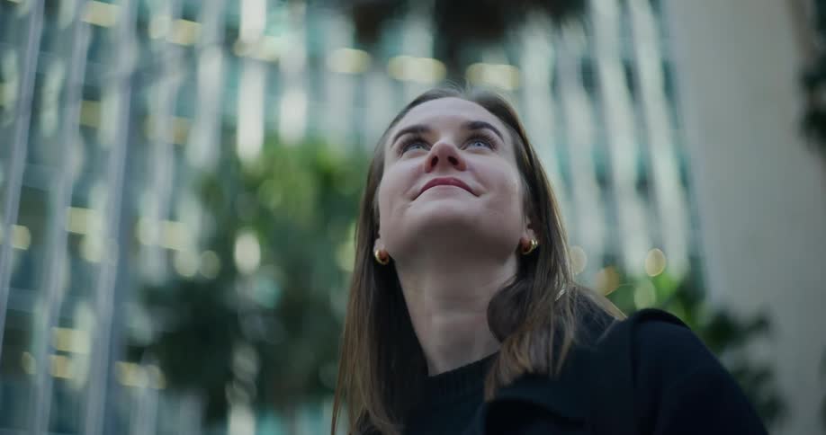 Portrait of a woman with happy facial expression looking up with buildings around