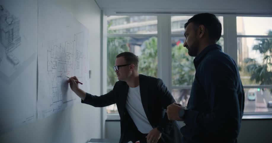 Two architects are sketching blueprints together