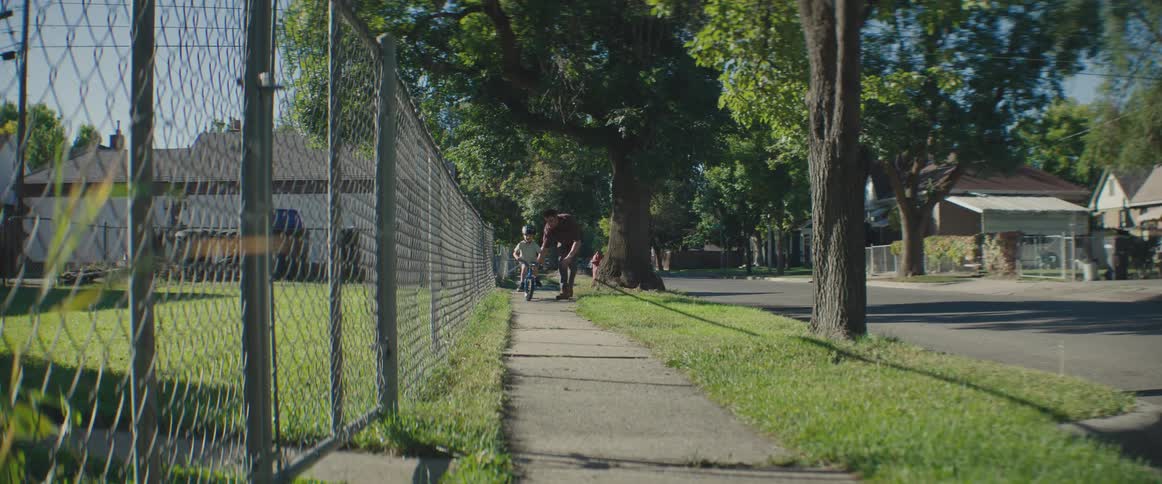 A father teaching his little son to ride a bike on a sidewalk