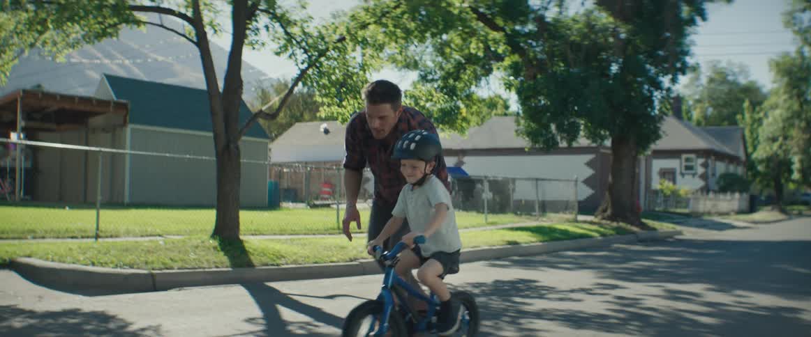 A father holds on to his sons bike in order to teach him how to ride