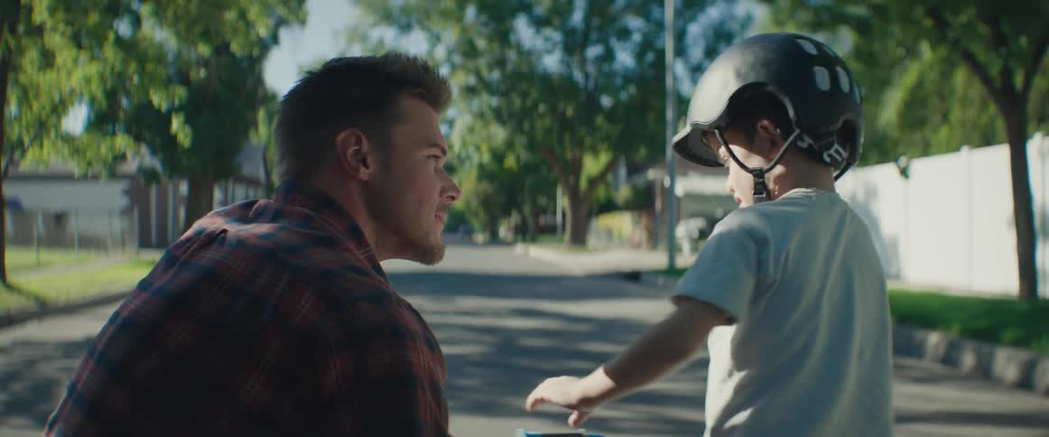 Father on the street talking to his son who is wearing a helmet