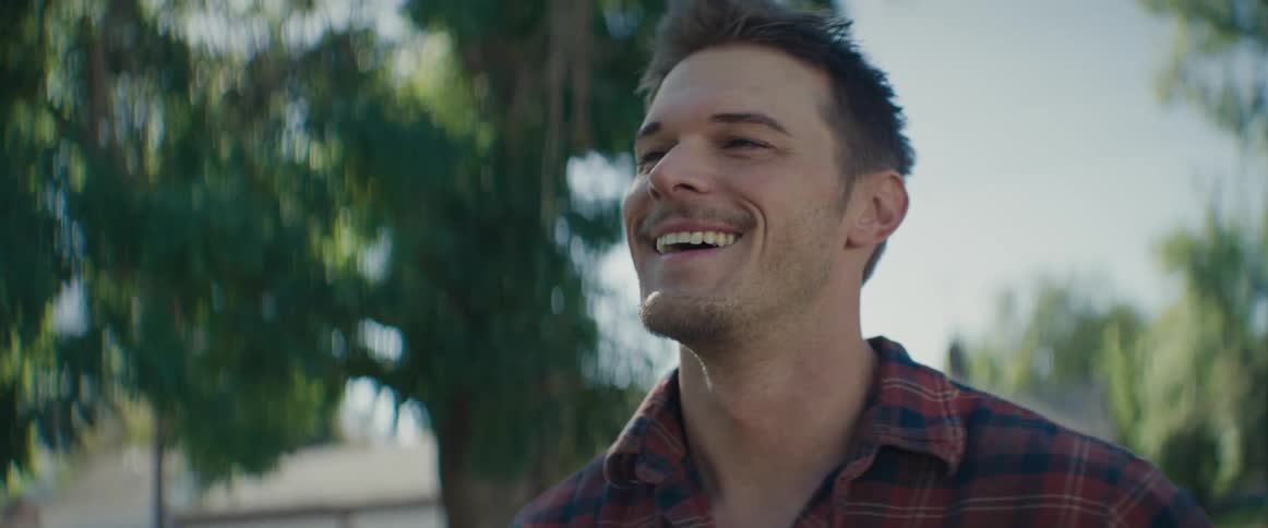 A man smiles and waves outside
