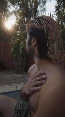 A man finishing meditating in his backyard by rubbing his hand on his chest then opening his eyes and looking to his side