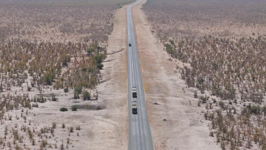 Trucks drive down a remote desert road
