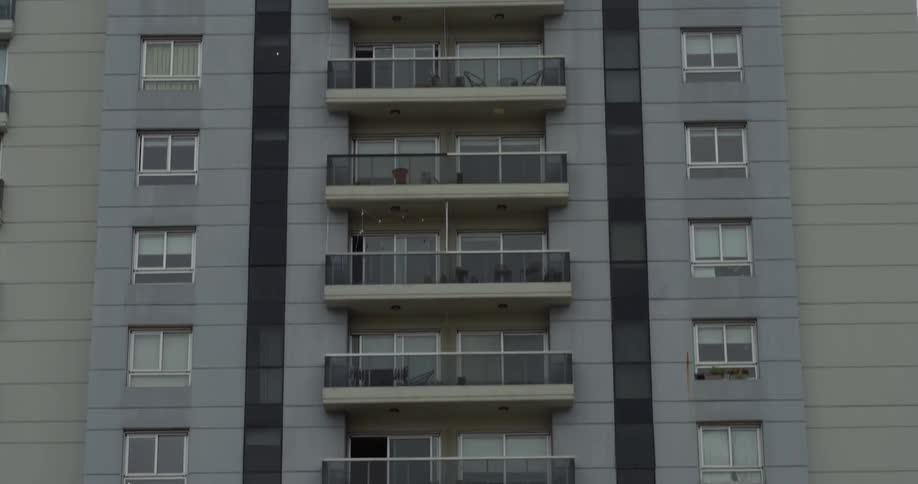 A gray apartment building with balconies on every floor