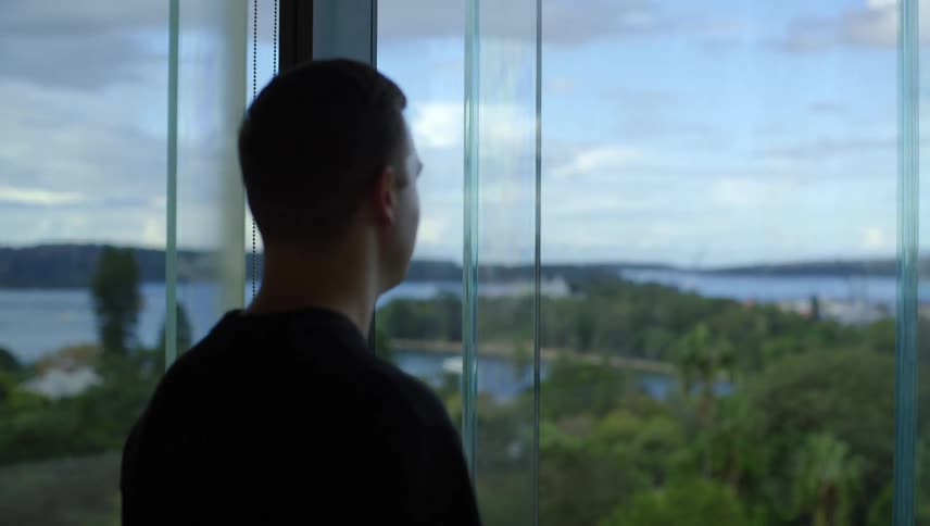 A man looks out the window at the shore