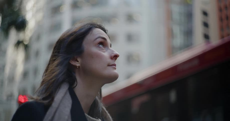Woman watching the city as a red bus passes by