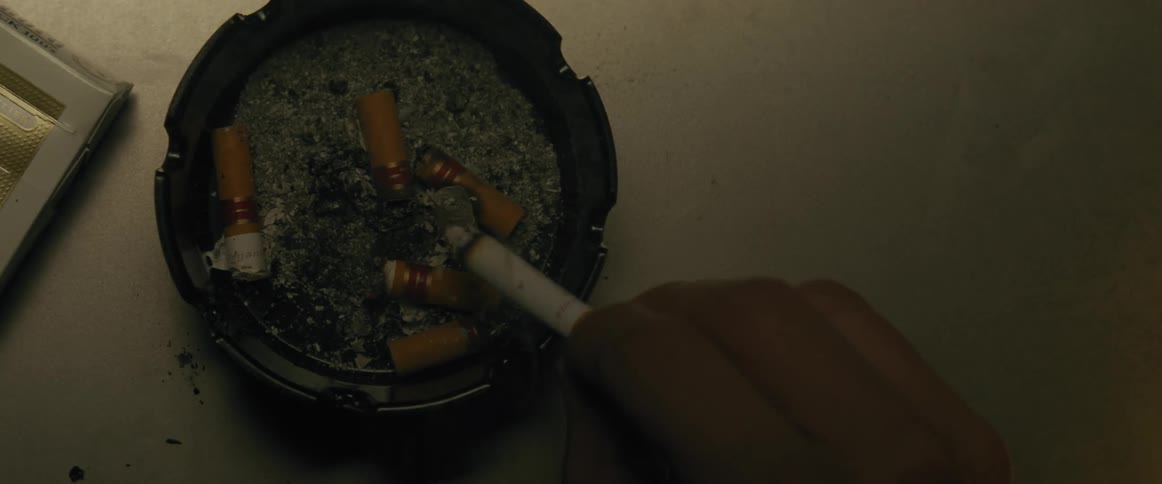 Hand holding a cigarette over an ashtray