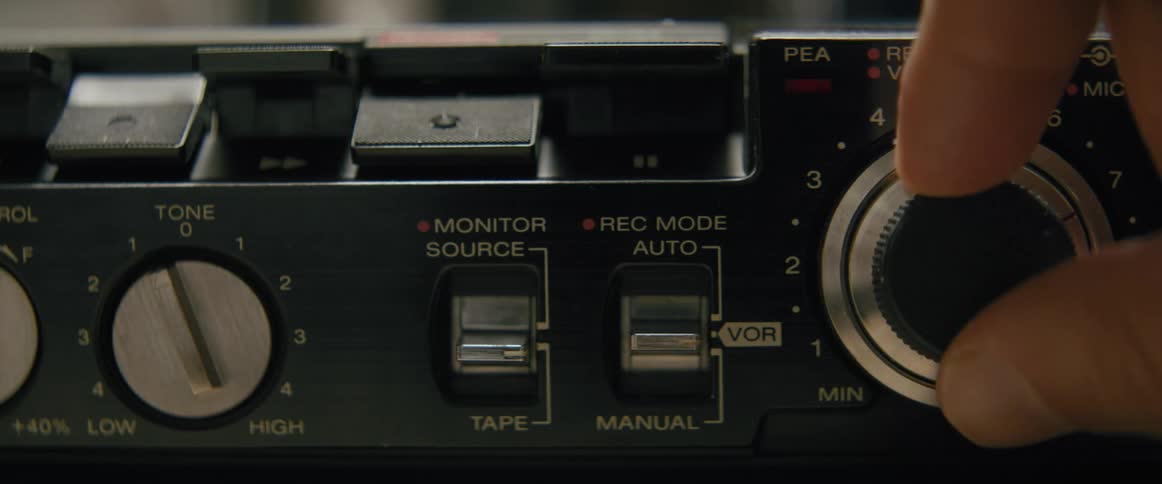 Hand turning a knob on a vintage audio recording electronics